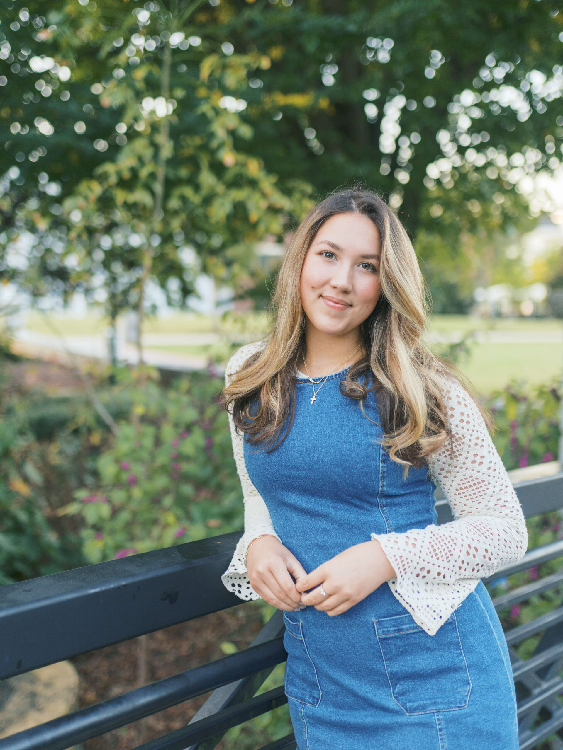 Class of 2025 senior girl leaning on a black railing surrounded by greenery in Downtown Lawrenceville, Georgia, during her morning senior photo session.