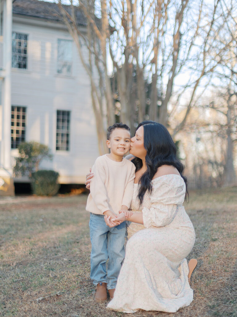 Gwinnett County maternity photos with mother kissing her son during outdoor sunset session in Dacula Georgia
