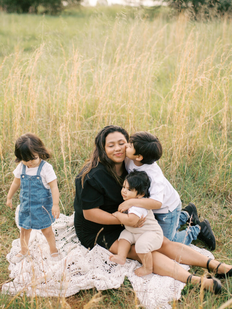 mom and her three young children sit in a field at a gwinnett county park